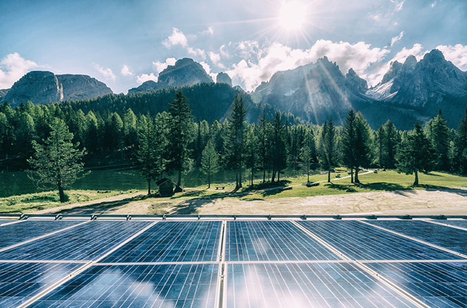 Solar panels in a field with a mountainous backdrop